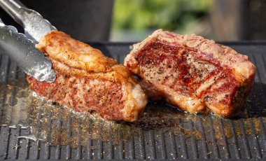 Sıcak elektrikli ızgara yüzeyinde taze ızgara sığır eti ve biftek.