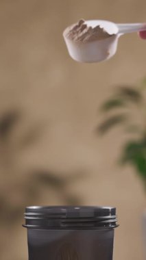 Protein tozu, ölçü kaşığından kabın içine dökülür. beyaz spor beslenmesi. Spor ya da diyet içeceği hazırlamak için kuru karışım.