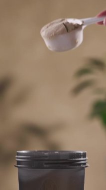 Protein tozu, ölçü kaşığından kabın içine dökülür. beyaz spor beslenmesi. Spor ya da diyet içeceği hazırlamak için kuru karışım.