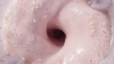 Çilekli ve muzlu, pembe milkshake karışımı. Üst Manzara. Ağır çekim. Sağlıklı protein içeceği konsepti, yiyecek yakın çekimi. Smoothie 'de protein tozu