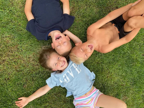 Troje Dzieci Leżących Zielonej Trawie Ziemi Uśmiechających Się — Zdjęcie stockowe