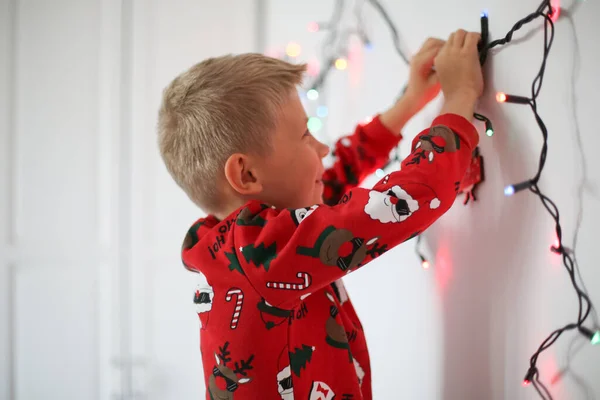 Αγόρι Κρατάει Μια Χριστουγεννιάτικη Γιρλάντα Στα Χέρια Του Και Στολίζει — Φωτογραφία Αρχείου
