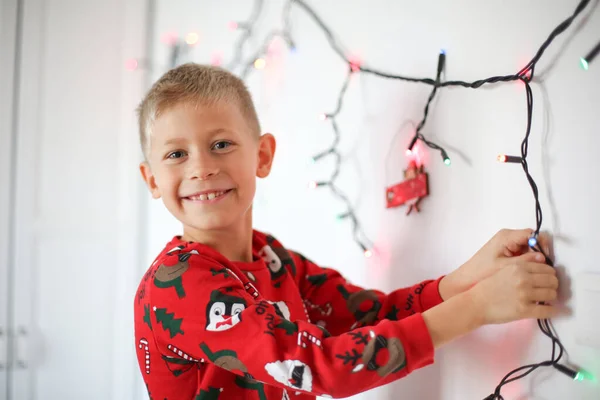 少年は手にクリスマスのガーランドを持ち ガーランドでクリスマスを飾る — ストック写真