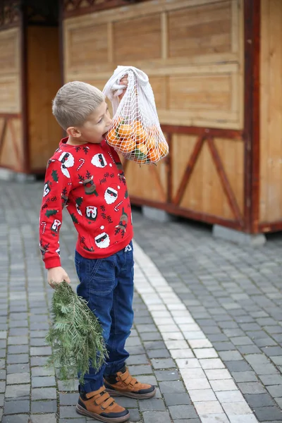 Χαριτωμένο Μικρό Αγόρι Χριστουγεννιάτικο Πουλόβερ Μανταρίνι Στην Αγορά Των Χριστουγέννων — Φωτογραφία Αρχείου