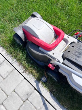 Electric Lawn mower on a green meadow. Garden equipment.