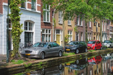 Delft, Hollanda - 12 Mayıs 2017: Arabalar ve bisikletler Delft caddesindeki kanal dolgusuna yansıtılarak park edildi. Delft, Hollanda