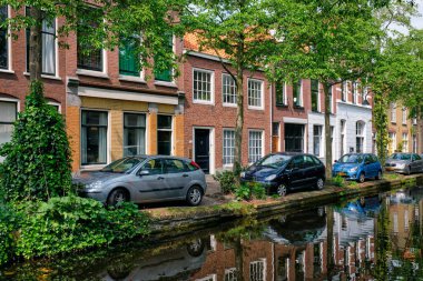 Delft, Hollanda - 12 Mayıs 2017: Arabalar ve bisikletler Delft caddesindeki kanal dolgusuna yansıtılarak park edildi. Delft, Hollanda