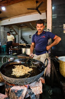 Pushkar, Hindistan - 7 Kasım 2019: Hint aşçı Murukku taze sokak yemeği yapar. Yağda kızartılmış lezzetli vejetaryen atıştırmalığı. Geleneksel lezzetli yemekler. Pushkar, Rajasthan, Hindistan