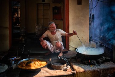 Pushkar, Hindistan - 7 Kasım 2019: Hindistan 'ın Rajasthan kentinde, Pushkar, Rajasthan caddesinde, kaşık tatlı ve haham tatlısı, yoğunlaştırılmış süt tabanlı yemekle karıştırılmış sokak yemekleri tezgahı aşçısı