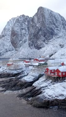 Norveç, Lofoten Adaları 'ndaki meşhur geleneksel balıkçı köyü Hamnoy' da kırmızı rorbu evleri var. Kışın kar yağarken