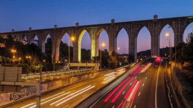 Campolide İstasyonu yakınlarındaki otoyol trafiğinin zaman aşımına uğraması ve arka planda Aguas Livres Aqueduct ile birlikte gece araba ışıkları izleri. Lizbon, Portekiz. Uzaklaştırma efekti