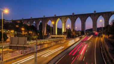 Campolide İstasyonu yakınlarındaki otoyol trafiğinin zaman aşımına uğraması ve arka planda Aguas Livres Aqueduct ile birlikte gece araba ışıkları izleri. Lizbon, Portekiz