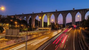 Campolide İstasyonu yakınlarındaki karayolu trafiğinin zaman aşımına uğraması ve arka planda Aguas Livres Aqueduct ile birlikte araba ışıkları izleri. Lizbon, Portekiz. Etkin büyüt