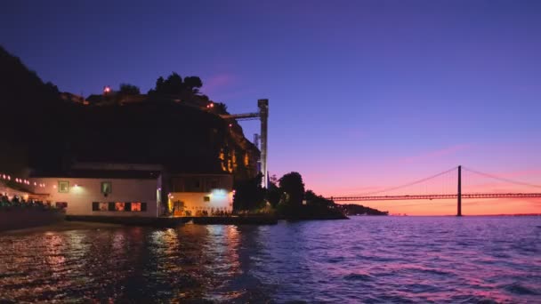 游览里斯本塔格斯河和波卡多文托电梯上25号德阿布里尔桥著名的旅游地标 以及晚上的海滨餐馆 葡萄牙里斯本 — 图库视频影像