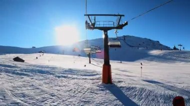 Kablolu sandalyede kayak kaldırmanın birinci şahıs bakış açısı FPV 'nin hızlı ileri etkisi alp kayağı için yükselir. Dolomitler 'de kayak yapan insanlarla kayak pisti. Kayak alanı Belvedere. Canazei, İtalya