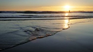 Atlantik Okyanusu 'nda gün batımında yüzen kadın silueti Fonte da Telha plajında dalgalanan dalgalarla, Costa da Caparica, Portekiz