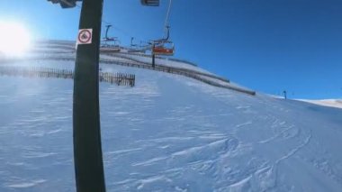 Kablolu sandalyede kayak kaldırmanın birinci şahıs bakış açısı FPV 'nin hızlı ileri etkisi alp kayağı için yükselir. Dolomitler 'de kayak yapan insanlarla kayak pisti. Kayak alanı Belvedere. Canazei, İtalya