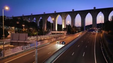 Campolide İstasyonu yakınlarındaki otoyol trafiği, Aguas Livres Aqueduct 'un da arka planda akşam saatlerinde trafik ışıkları. Lizbon, Portekiz