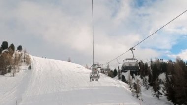 Kablolu sandalyede kayak kaldırmanın FPV bakış açısı Dolomitlerde alp kayağı için yükseliyor. İtalya 'da Dolomitler' de kayak yapan insanlarla kayak merkezi. Kayak alanı Belvedere. Canazei, İtalya