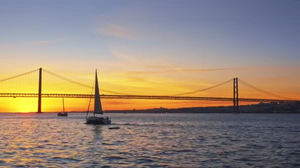 位于塔古斯河上塞图巴尔半岛的里斯本著名旅游胜地里斯本的阿布里尔桥25号的景观 与夕阳西下路过的游艇轮廓相连 葡萄牙里斯本 — 图库视频影像