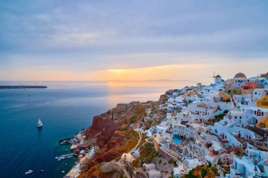 Famous greek iconic selfie spot tourist destination Oia village with traditional white houses and windmills in Santorini island on sunset in twilight, Greece clipart