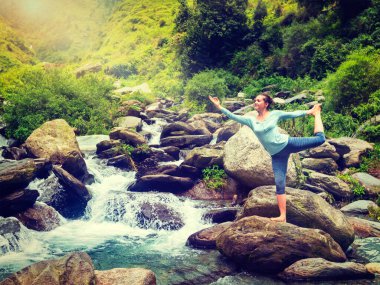 Yoga yapan kadın, yoga yapan Natarajasana dans dengesi efendisi Himalayalar 'daki şelalenin önünde poz veriyor. Vintage retro efekti filtrelenmiş hipster tarzı resim.