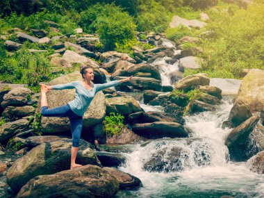 Yoga yapan kadın, yoga yapan Natarajasana dans dengesi efendisi Himalayalar 'daki şelalenin önünde poz veriyor. Vintage retro efekti filtrelenmiş hipster tarzı resim.