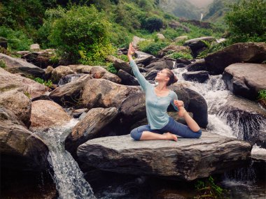 Yoga açık havada - sportif genç kadının germe yoga asana Eka pada rajakapotasana - tek bacaklı Kral güvercin tropik şelale poz yapması yerleştirmek. Retro vintage etkisi filtre uygulanmış hippi tarzı görüntü.