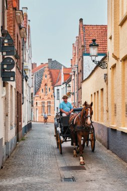 Bruges, Belçika - 29 Mayıs 2018: Brugge caddesinde eski evleri ve kaldırım taşı yolu olan turistler için at arabası