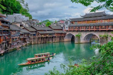 FENGHUANG, ÇİN - 23 Nisan 2018: Çin turizm merkezi - Feng Huang Antik Kenti (Phoenix Antik Kenti) Tuo Jiang Nehri üzerinde köprü ve turist botu ile. Hunan Eyaleti, Çin