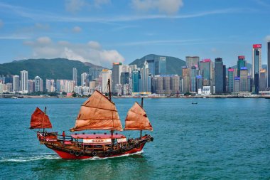 Hong Kong, Çin - 1 Mayıs 2018: Günbatımında Victoria Limanı üzerindeki Hong Kong şehir merkezi gökdelenleri ve turist hurda teknesi. Hong Kong, Çin