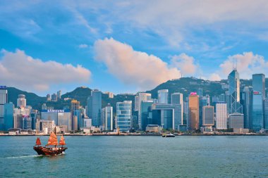 Hong Kong, Çin - 1 Mayıs 2018: Günbatımında Victoria Limanı üzerindeki Hong Kong şehir merkezi gökdelenleri ve turist hurda teknesi. Hong Kong, Çin