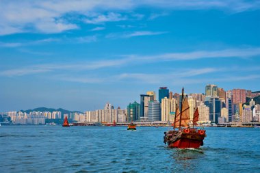 Hong Kong, Çin - 1 Mayıs 2018: Günbatımında Victoria Limanı üzerindeki Hong Kong şehir merkezi gökdelenleri ve turist hurda teknesi. Hong Kong, Çin