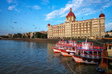 Mumbai, Hindistan - 31 Ekim 2019: Ünlü Taj Oteli 'nin önündeki turist tekneleri ve uçan güvercinler