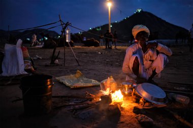 Pushkar, Hindistan - 6 Kasım 2019: Hindistan kırsal kesiminde geceleyin Pushkar deve fuarı Pushkar Mela 'da kamp ateşiyle yakılan insan ve develer - yıllık ünlü deve ve ve ve ve hayvan fuarı ve turistik eğlence merkezi