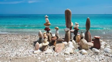 Denge ve uyum kavramı. Doğada mavi denizin sahil kıyısındaki çakıl taşı yığınları. Taş istifleme meditasyon sanatı. Kamera yatay doli takip ediyor. Agia Kiriaki plajı, Milos adası, Yunanistan