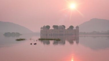 Meşhur Hint turist tarihi Jal Mahal Su Sarayı ve Jaipur 'da güneşin doğuşunda dingin bir gül gökyüzü. Etraftaki ördekler ve kuşlar dingin sabahın tadını çıkarıyorlar. Jaipur, Rajasthan, Hindistan