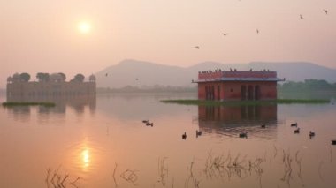 Jaipur 'da gün doğumunda ünlü Hint turist tarihi Jal Mahal Su Sarayı. Etraftaki ördekler ve kuşlar dingin sabahın tadını çıkarıyorlar. Jaipur, Rajasthan, Hindistan