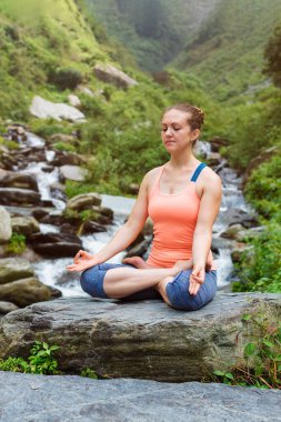 Hatha yoga asana Padmasana açık havada tropik şelale, kadında