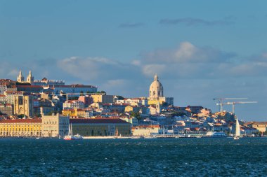 Almada 'dan Tagus nehrinin üzerindeki Lizbon manzarası. Günbatımında yatlarla turist botları. Lizbon, Portekiz