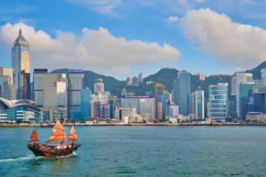 Hong Kong, Çin - 1 Mayıs 2018: Günbatımında Victoria Limanı üzerindeki Hong Kong şehir merkezi gökdelenleri ve turist hurda teknesi. Hong Kong, Çin