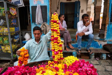 Pushkar, Hindistan - 7 Kasım 2019 - Hintli çiçekçi çiçek satıcısı çiçek pazarındaki Pushkar sokaklarında dini amaçlar için çiçek satıyor. Pushkar, Rajasthan, Hindistan