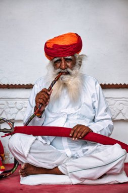 JODHPUR, INDIA - 13 Kasım 2019: Mehrangarh kalesinde sakallı yaşlı Hintli adam nargile içiyor. Nargile kavramının Hindistan 'da ortaya çıktığı düşünülüyor.