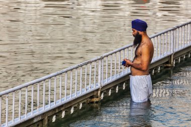 AMRITSAR, INDIA - 26 AĞUSTOS 2011: Sikh adam Harmandir Sahib 'in etrafındaki kutsal tankta namaz kılıyor ve banyo yapıyor