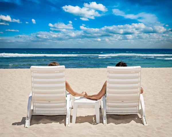 新婚旅行のリゾートの概念 ビーチでカップルの椅子海の近く手を繋いで — ストック写真