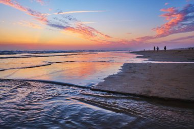 Atlantik Okyanusu gün batımından sonra dalgalanan dalgalarla Fonte da Telha Sahili, Costa da Caparica, Portekiz