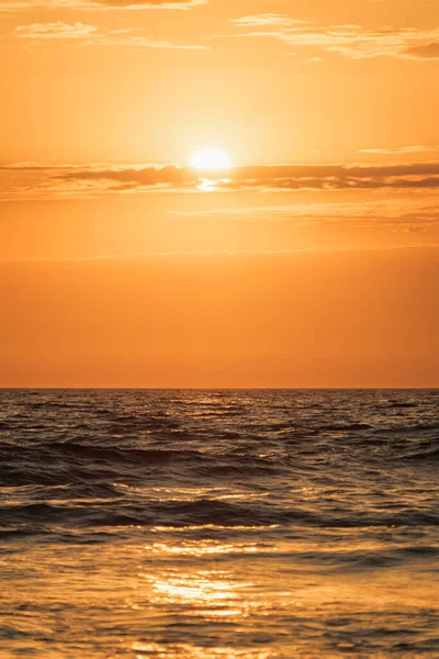 Ocean waves on sunset with setting sun background