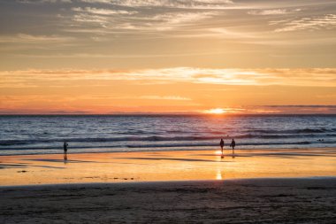 Fotoğrafçı siluetiyle Atlantik Okyanusu 'nda gün batımı Fonte da Telha Sahili, Costa da Caparica, Portekiz' deki dalgaların dalgalanan görüntülerini çekiyor.