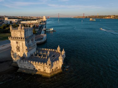 Belem Kulesi 'nin Tagus Nehri' nin kıyısında gün batımında turist botu ve kargo konteynır gemisiyle Lisboa 'nın ünlü turizm beldesi ve turizm merkezi. Lizbon, Portekiz