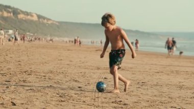 Çocuk Atlantik Okyanusu sahilinde topla oynarken eğleniyor. Fonta da Telha plajı, Costa da Caparica, Portekiz